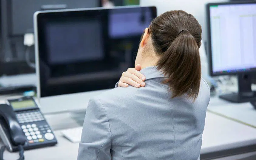 Woman experiencing neck pain at her desk